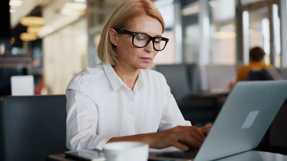 Người viết email tiếng Anh công việc trên laptop trong văn phòng